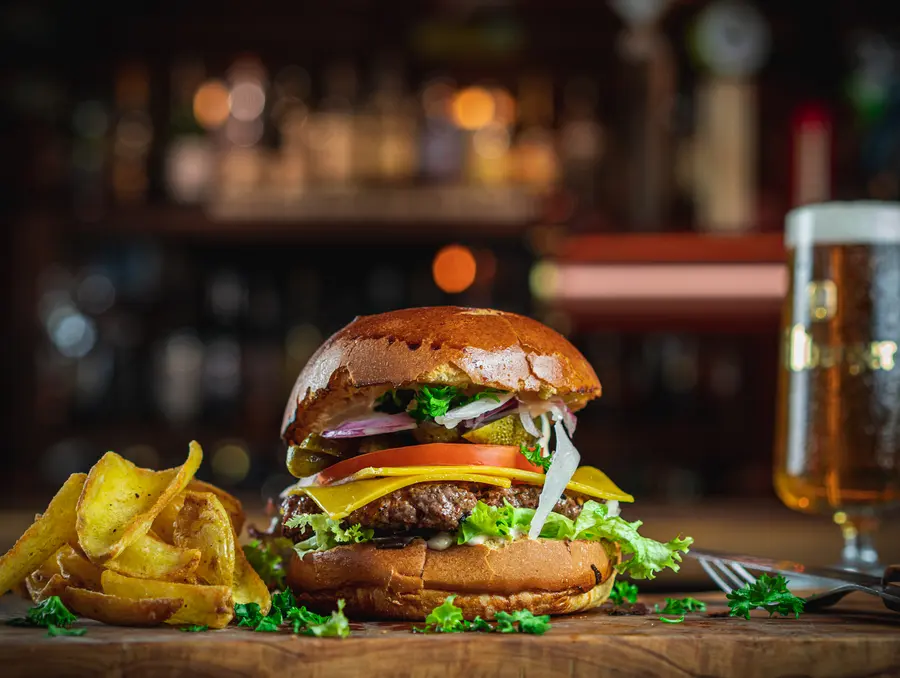 Cheeseburger mit doppelt Cheddar, roten Zwiebelringen und Tomate